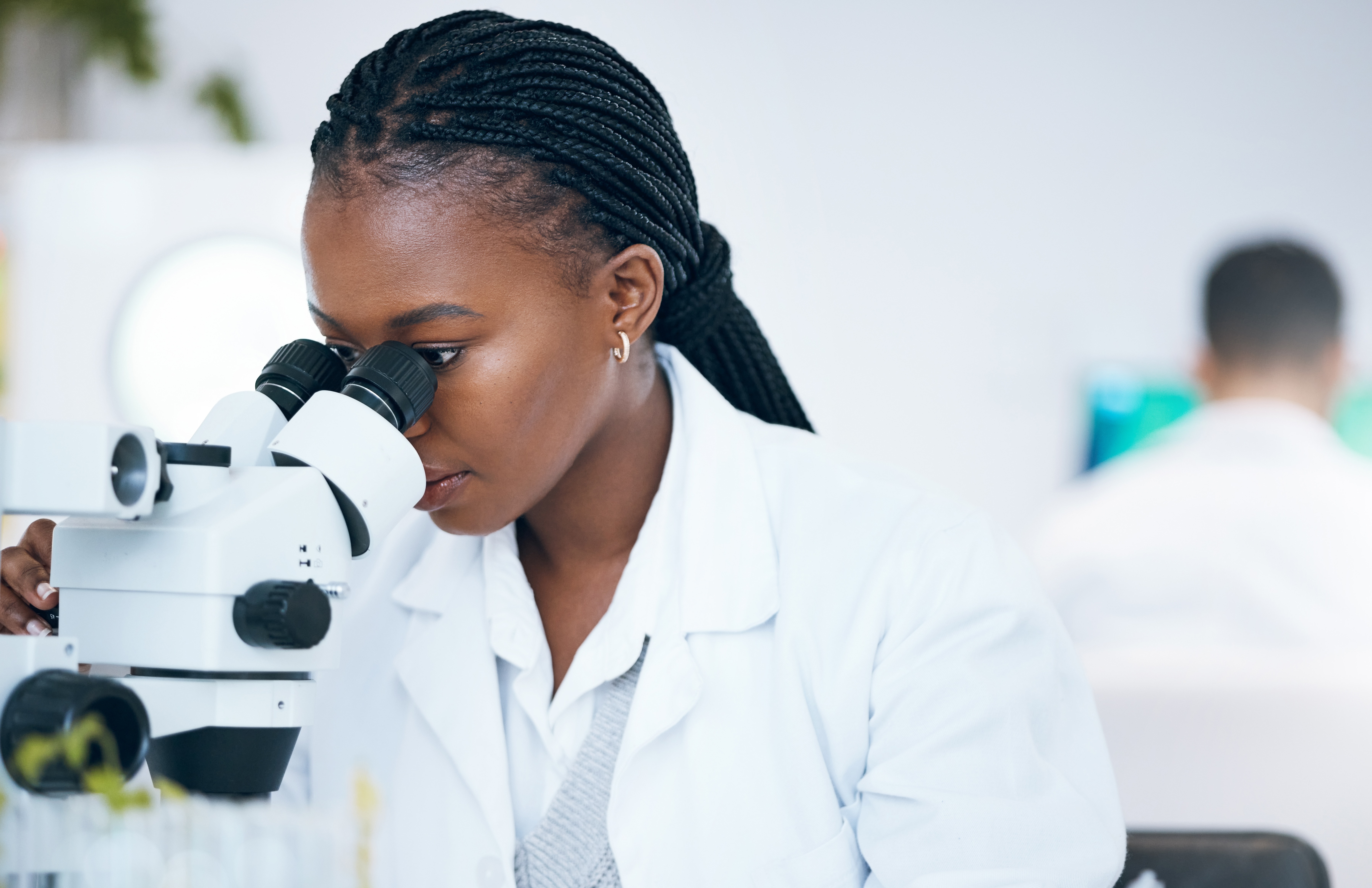 Medical science, black woman and microscope in laboratory for research, analytics and medicine. Woman, doctor and scientist study at work for an investigation, healthcare and futuristic mock up space.