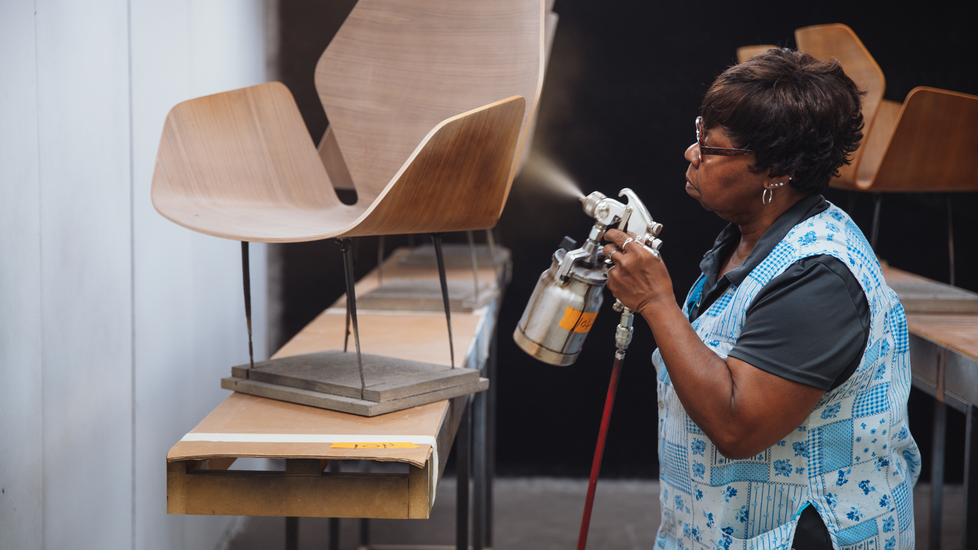 Manufacturing worker sprays a newly made wooden chair.